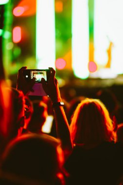 Telefon kayıtlarıyla birlikte canlı müzik festivali. Akıllı telefonla fotoğraf çeken insanlar..