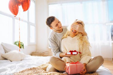 Genç çift evdeki oturma odasında kanepede otururken hediyelerini değiş tokuş ediyorlar. Bir adam sevgilisine hediye kutusu veriyor. Birlikte romantik bir gün. Sevgililer Günün kutlu olsun..