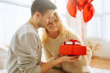 Genç çift evdeki oturma odasında kanepede otururken hediyelerini değiş tokuş ediyorlar. Bir adam sevgilisine hediye kutusu veriyor. Birlikte romantik bir gün. Sevgililer Günün kutlu olsun..