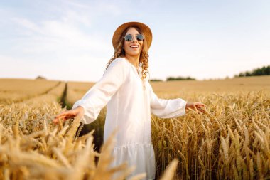 altın buğday tarlasında genç güzel kadın. yaz kavramı, özgürlük, sıcaklık, hasat, rekreasyon, tarım.