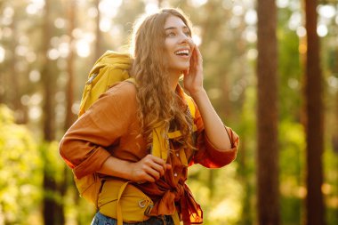 Sırt çantalı kadın turist ormandaki temiz havada dinleniyor, mutluluğu ve doğayla bağlantıyı hissediyor..
