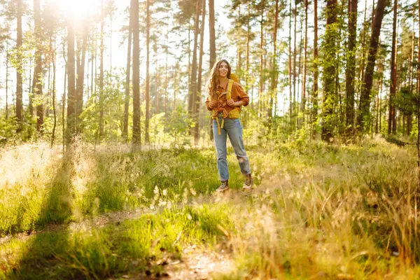 Sırt çantalı kadın turist ormandaki temiz havada dinleniyor, mutluluğu ve doğayla bağlantıyı hissediyor..