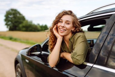 Arabayla ya da karavanla seyahat eden genç bir kadın, açık pencere kırsal alanda temiz hava alıyor. Seyahat macerası..