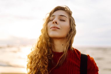 Soğuk havada kumsalda sırt çantalı güzel bir kadının portresi. Denize yakın bir sonbahar. Sakinlik ve sükunet. Seyahat, turizm konsepti.