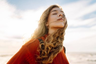 Soğuk havada kumsalda sırt çantalı güzel bir kadının portresi. Denize yakın bir sonbahar. Sakinlik ve sükunet. Seyahat, turizm konsepti.