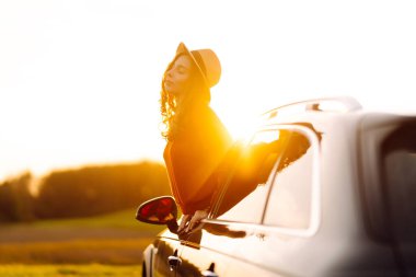 Mutlu kadın araba penceresinden gün batımını seyretmeyi sever. Yaşam tarzı, seyahat, turizm, doğa, aktif yaşam.