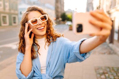 Güzel kadın gezgin telefon kullanıyor, selfie çekiyor, eski şehir caddesinde yürüyor. Blogculuk, teknoloji, yaşam tarzı, seyahat, turizm, aktif yaşam