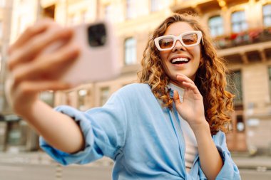 Güzel kadın gezgin telefon kullanıyor, selfie çekiyor, eski şehir caddesinde yürüyor. Blogculuk, teknoloji, yaşam tarzı, seyahat, turizm, aktif yaşam