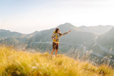 Kadın turist yaz güneşli bir günde dağın tepesinde güneş ışığı altında yürüyor. Güzel dağlar manzara. Macera aktif