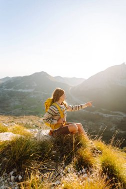 Kadın turist yaz güneşli bir günde dağın tepesinde güneş ışığı altında yürüyor. Güzel dağlar manzara. Macera aktif
