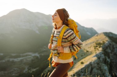 Kadın turist yaz güneşli bir günde dağın tepesinde güneş ışığı altında yürüyor. Güzel dağlar manzara. Macera aktif
