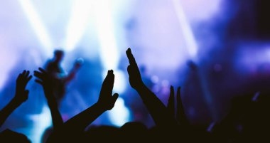 Konserde kalabalık. Sahne ışıkları ve eller havaya. İnsanlar eğleniyor. Taraftarlar müzik festivalinin tadını çıkarıyor.
