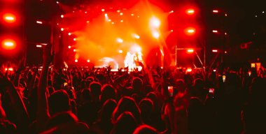 Konserde kalabalık. Sahne ışıkları ve eller havaya. İnsanlar eğleniyor. Taraftarlar müzik festivalinin tadını çıkarıyor.