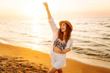 Genç bayan sahilde tatilin tadını çıkarıyor. Gün batımında deniz manzarası ve güzel bir gökyüzü. Seyahat, hafta sonu, rahatlama ve yaşam tarzı konsepti.