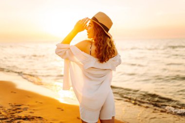 Genç bayan sahilde tatilin tadını çıkarıyor. Gün batımında deniz manzarası ve güzel bir gökyüzü. Seyahat, hafta sonu, rahatlama ve yaşam tarzı konsepti.