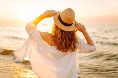 Genç bayan sahilde tatilin tadını çıkarıyor. Gün batımında deniz manzarası ve güzel bir gökyüzü. Seyahat, hafta sonu, rahatlama ve yaşam tarzı konsepti.
