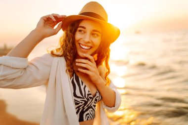 Genç bayan sahilde tatilin tadını çıkarıyor. Gün batımında deniz manzarası ve güzel bir gökyüzü. Seyahat, hafta sonu, rahatlama ve yaşam tarzı konsepti.