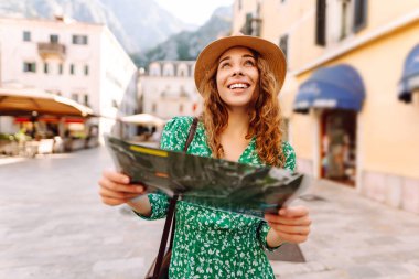 Şehir şehir topografik haritayla gezen maceraperest kadın. Modayı takip eden kadın yazın yurt dışına seyahat ederken haritada yön arıyor. Turizm.