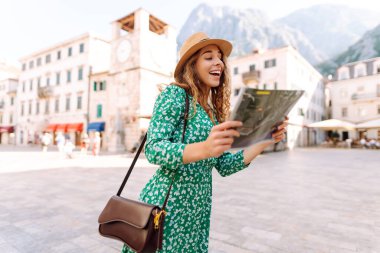 Şehir şehir topografik haritayla gezen maceraperest kadın. Modayı takip eden kadın yazın yurt dışına seyahat ederken haritada yön arıyor. Turizm.