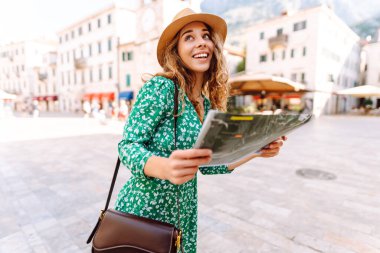 Şehir şehir topografik haritayla gezen maceraperest kadın. Modayı takip eden kadın yazın yurt dışına seyahat ederken haritada yön arıyor. Turizm.