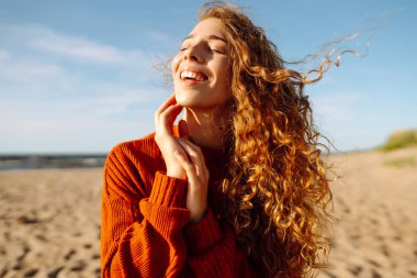 Sunny Beach Macerası. Soğuk, güneşli bir havada sahilde gülümseyen bir kadının portresi. Bahar geldi. Seyahat, hafta sonu, rahatlama ve yaşam tarzı konsepti.