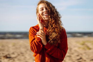 Sunny Beach Macerası. Soğuk, güneşli bir havada sahilde gülümseyen bir kadının portresi. Bahar geldi. Seyahat, hafta sonu, rahatlama ve yaşam tarzı konsepti.