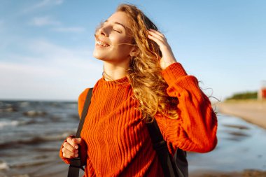Sunny Beach Macerası. Soğuk, güneşli bir havada sahilde gülümseyen bir kadının portresi. Bahar geldi. Seyahat, hafta sonu, rahatlama ve yaşam tarzı konsepti.