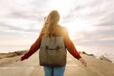 Deniz aşırı deniz fenerine bakan genç bir kadın. Seyahat, hafta sonu, rahatlama ve yaşam tarzı konsepti.