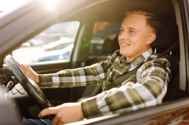 Mutlu adam yeni arabasında sürücü koltuğunda rahatça oturuyor. Araba yolculuğu, yaşam tarzı konsepti. Araba paylaşım kavramı.