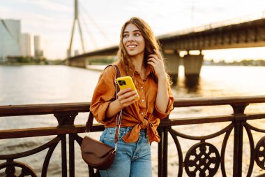 Kadın portresi duvar seti üzerinde telefon yürüyüşü yapar. Telefonu olan şık bir kadın. Tatil kavramı, teknoloji, hafta sonu.