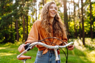 Yeşil şehir parkında kaldırımda bisiklet süren mutlu kadın. Etkin yaşam tarzı kavramı.
