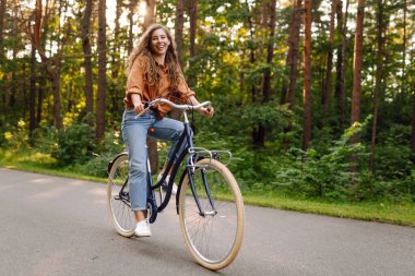 Yeşil şehir parkında kaldırımda bisiklet süren mutlu kadın. Etkin yaşam tarzı kavramı.