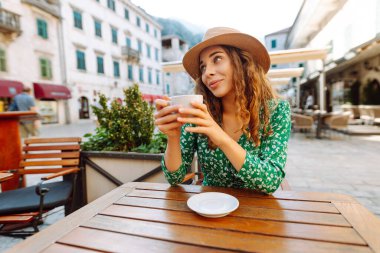 Şehirdeki sokak kafesinde kahve içen genç bir kadın. Kahvaltıda. İnsanlar, moda, yaşam tarzı, seyahat ve tatil kavramı