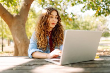 Şehir parkında oturan, laptopta çalışan ya da ders çalışan çekici bir kadın. Parkta çalışan serbest çalışan biri. Çevrim içi rota