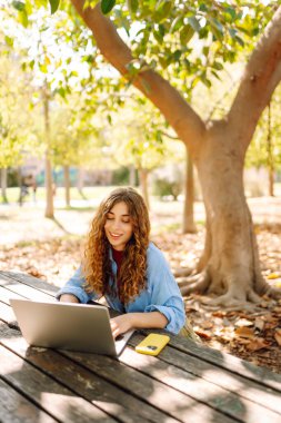 Şehir parkında oturan, laptopta çalışan ya da ders çalışan çekici bir kadın. Parkta çalışan serbest çalışan biri. Çevrim içi rota