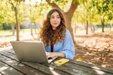 Şehir parkında oturan, laptopta çalışan ya da ders çalışan çekici bir kadın. Parkta çalışan serbest çalışan biri. Çevrim içi rota