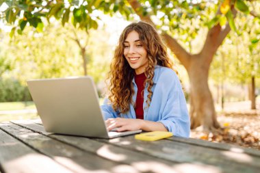 Şehir parkında oturan, laptopta çalışan ya da ders çalışan çekici bir kadın. Parkta çalışan serbest çalışan biri. Çevrim içi rota