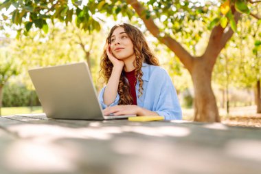 Şehir parkında oturan, laptopta çalışan ya da ders çalışan çekici bir kadın. Parkta çalışan serbest çalışan biri. Çevrim içi rota