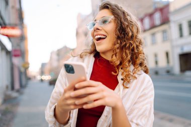 Şehir caddesinde telefon kullanan güzel bir genç kadının portresi. İletişim, sosyal ağlar, blog yazma, online alışveriş kavramı.