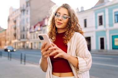Şehir caddesinde telefon kullanan güzel bir genç kadının portresi. İletişim, sosyal ağlar, blog yazma, online alışveriş kavramı.