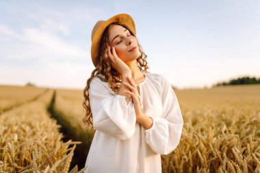 Altın buğday tarlasında özgür hisseden şık bir yaz elbisesi içinde moda bir kadın. Moda, cazibe, yaşam tarzı konsepti