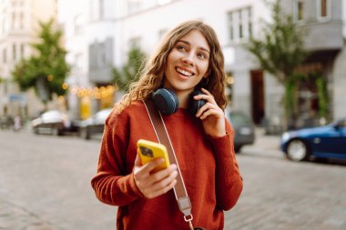 Genç, neşeli, güzel bir kadın dans ediyor ve kulaklıkla en sevdiği müziği dinliyor. Seyahat, turizm, teknoloji, blog konsepti. Kasaba yaşam tarzları.