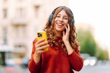 Genç, neşeli, güzel bir kadın dans ediyor ve kulaklıkla en sevdiği müziği dinliyor. Seyahat, turizm, teknoloji, blog konsepti. Kasaba yaşam tarzları.