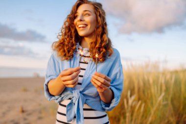 Gün batımında sahilde maytaplı güzel bir kadın. Yaz tatili, parti, tatil, rahatlama ve yaşam tarzı konsepti.