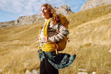 Kadın turist, sırt çantasıyla dağlarda durmuş manzarayı seyrediyor. Seyahat, yaşam tarzı, başarı, macera.