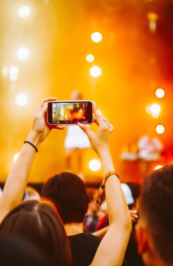 Telefon kayıtlarıyla birlikte canlı müzik festivali. Akıllı telefonla fotoğraf çeken insanlar..