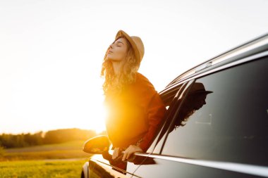 Güzellik kraliçesi gün batımında arabayla gezmekten hoşlanır. Neşe dolu. Yaşam tarzı, seyahat, turizm, doğa, aktif yaşam