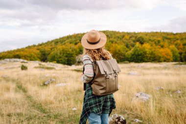 Kadın turistin sırt çantasıyla dağlarda durup manzarayı seyrettiği arka plan görüntüsü. Avrupa seyahati. Yaşam tarzı, tatil, turizm, doğa, aktif yaşam