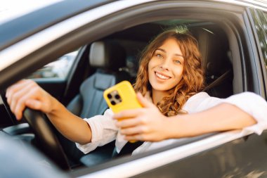 Kadın sürücü arabada akıllı telefon kullanıyormuş. Yönlendirme. Hareket konsepti, modern teknoloji