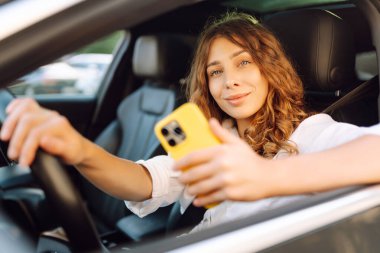 Kadın sürücü arabada akıllı telefon kullanıyormuş. Yönlendirme. Hareket konsepti, modern teknoloji